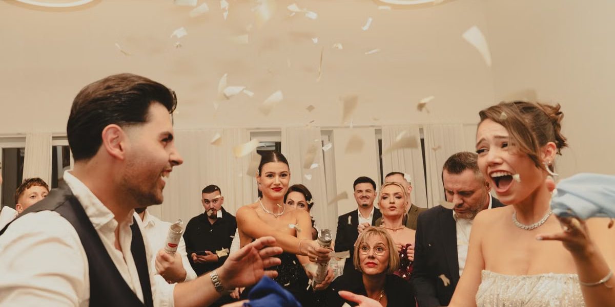 Bride and groom celebrating at a lively indoor wedding reception with friends and family.