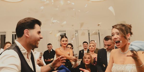 Bride and groom celebrating at a lively indoor wedding reception with friends and family.